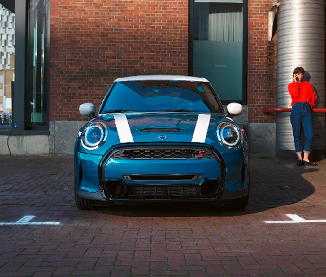 A front view of the MINI Hardtop 4 Door parked in front of a brick building.